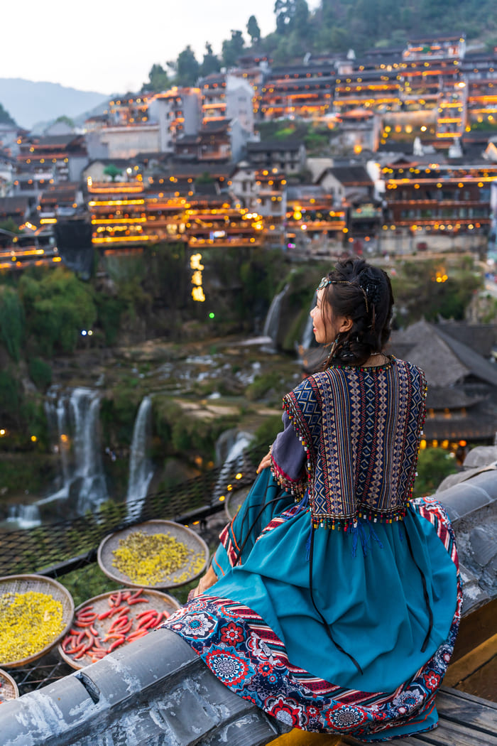 mujer posando frente al paisaje en ciudad lijiang, China